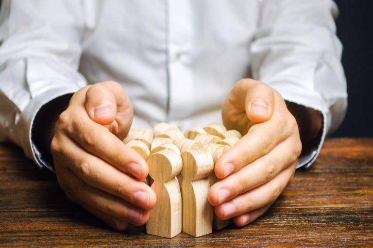 man holding wooden people figurines