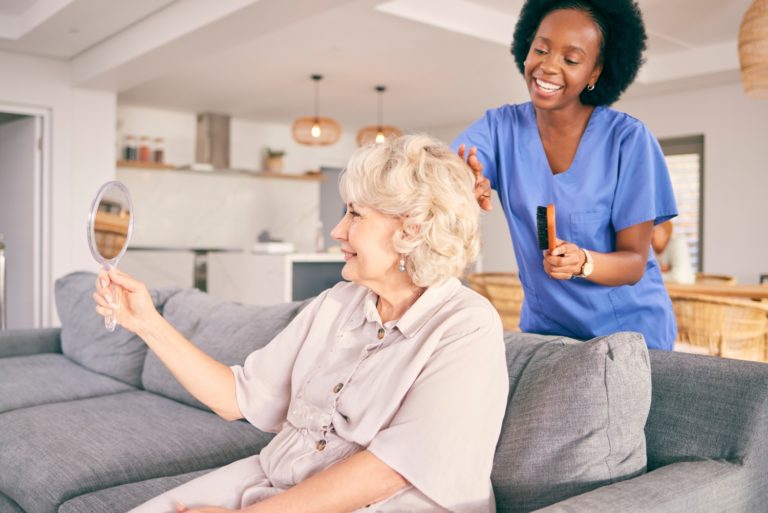 Caregiver brush hair of senior woman in the living room of the modern retirement home for self care