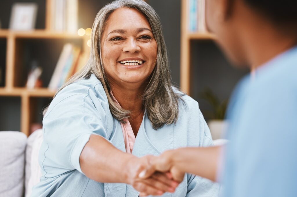 elderly woman shaking hands with home care team or employee, concept of client intake