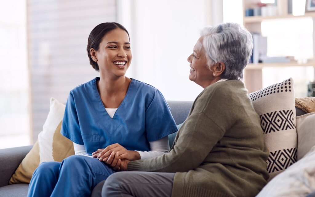 lady caregiver smiling to elderly woman while sitting in the living room
