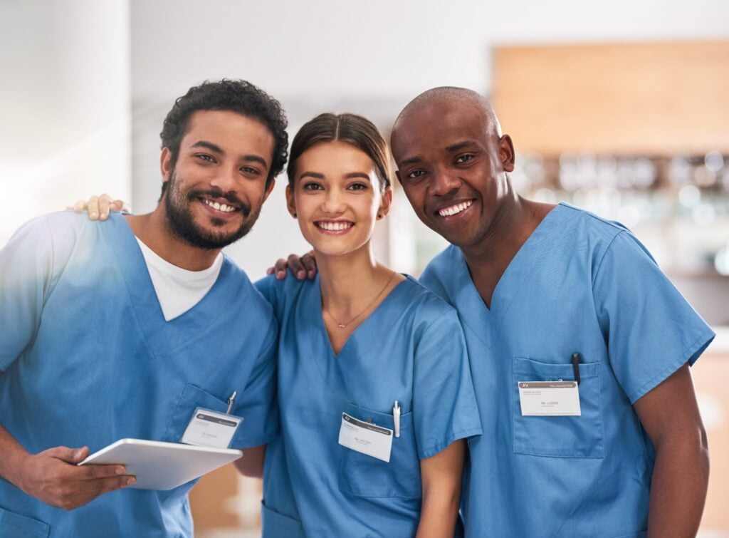 group of smiling caregivers while holding a tablet device equipped with home care software