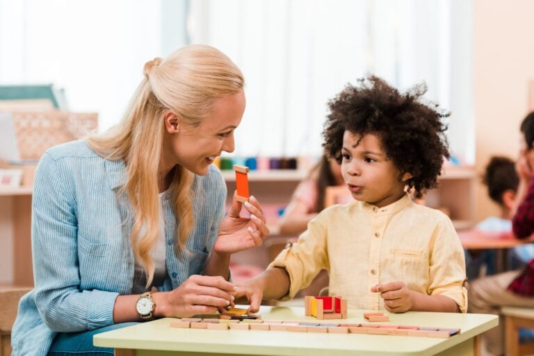 child playing educational game with smiling nanny beside him