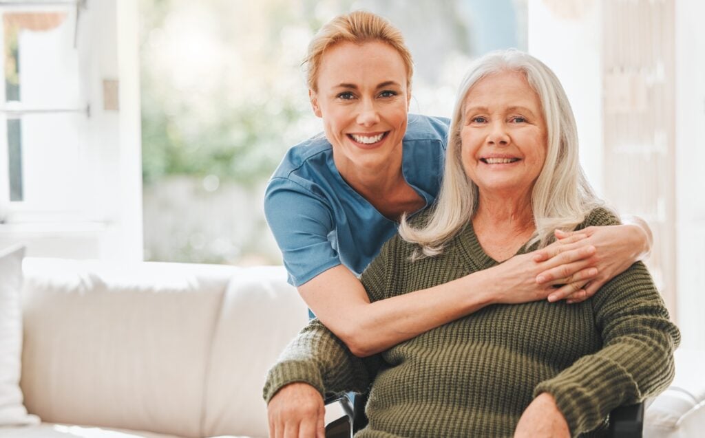 female caregiver hugging an elderly woman client in a wheelchair, concept of home care (1)