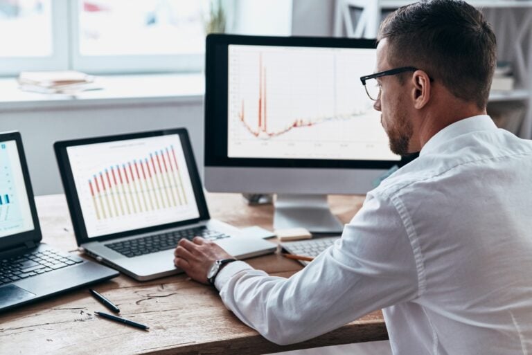 male employee looking at computer screens projecting real time data