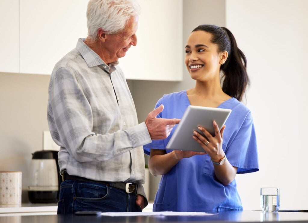 young caregiver entering data on a tablet during a house visit