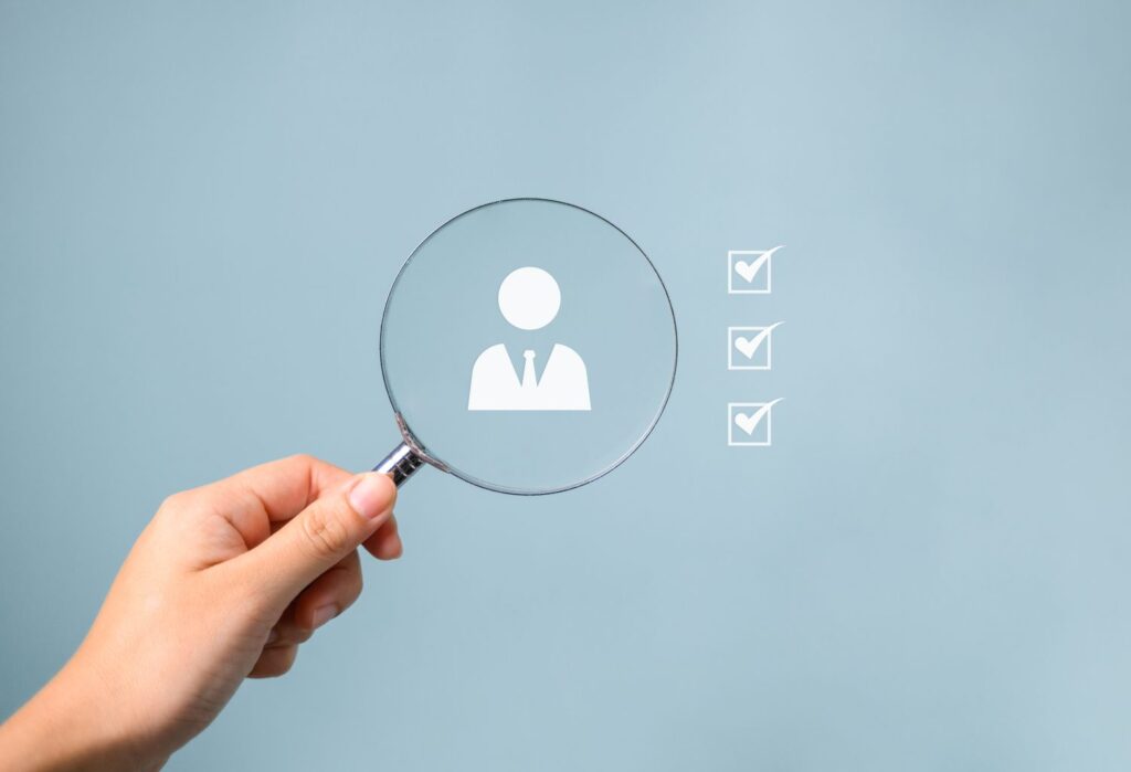 Hand holding magnifying glass for concept of human resources, searching and selecting caregivers