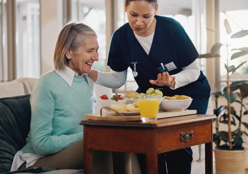 caregiver assisting an elderly woman with breakfast, concept of support and nutrition