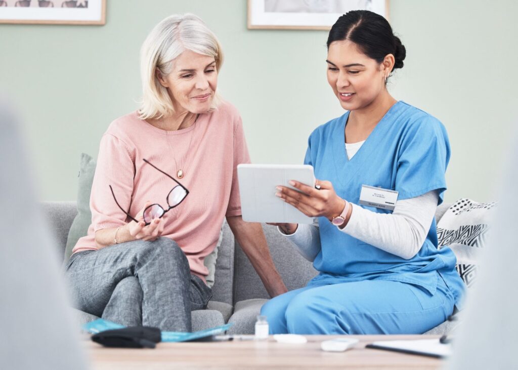 female caregiver using a tablet while sitting next to female client