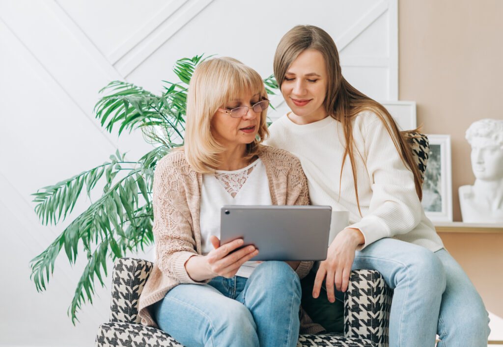 Mom and adult daughter using tablet together, concept of family portal