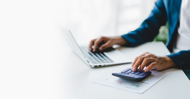 close up shot of business person using laptop with calculator, concept of accounting and billing