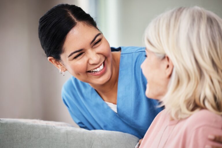 Shot of a female caregiver smiling while talking to elderly woman