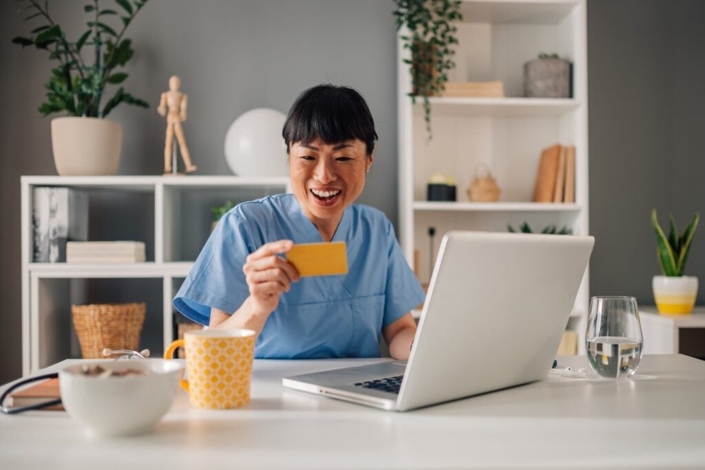 caregiver similing while holding payment card at home, concept of flexible payment processes