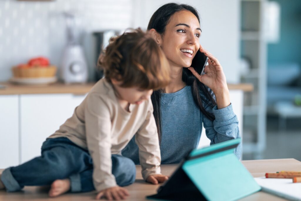 mother looking and smiling at son while using mobile phone to make a phone call