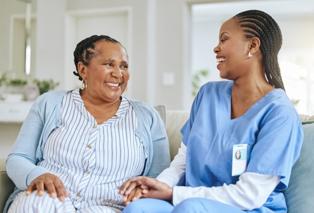 senior woman smiling and looking satisfied while receiving care from caregiver