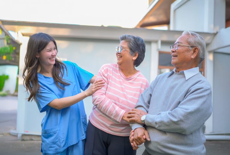 caregiver smiling and spending time with elderly couple at a senior living community