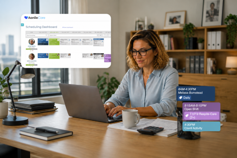 Adult female employee seated at a desk in an office, typing on a laptop while accessing a client dashboard for home care software