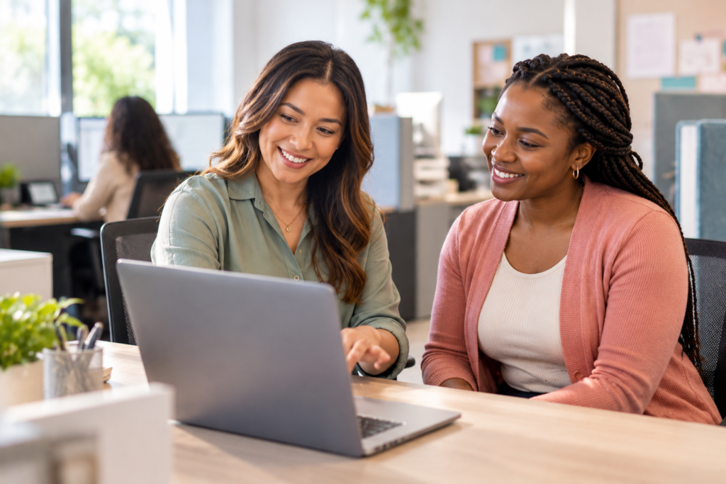 Home care agency administrator assists a new caregiver with digital recruitment and onboarding using a laptop in a modern office
